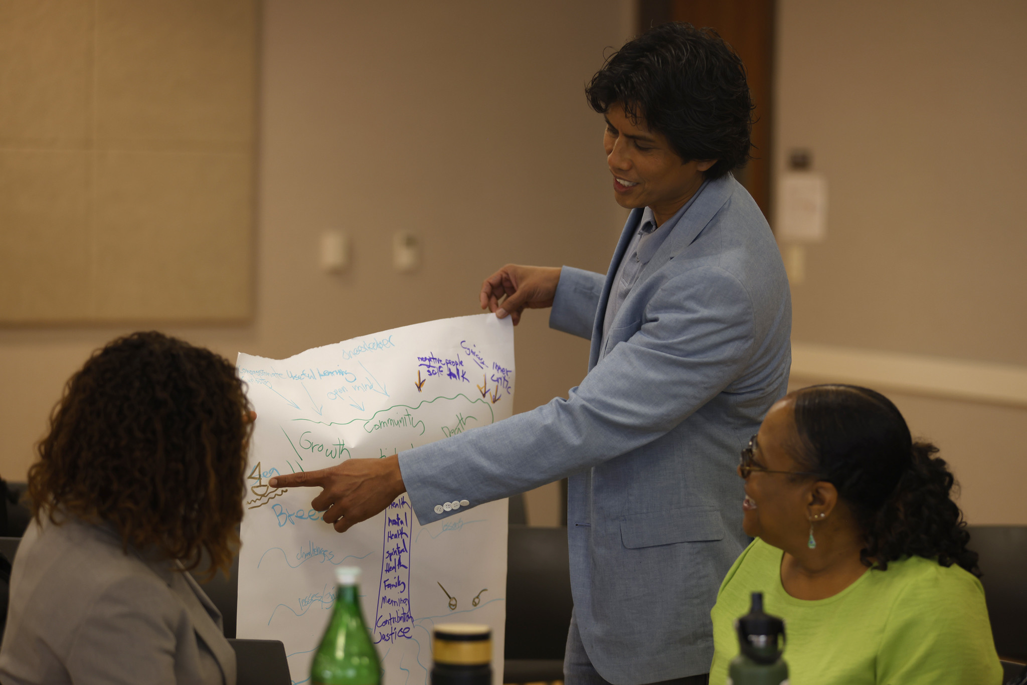 Three attendees look at a drawing depicting growth in professional development.