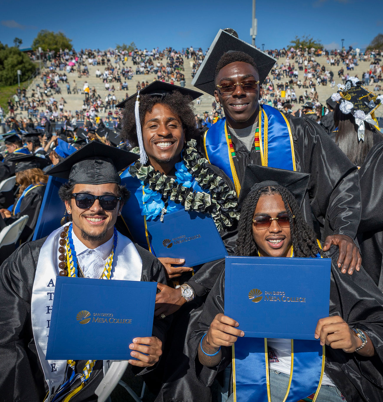 Four grads hoding up their degrees.