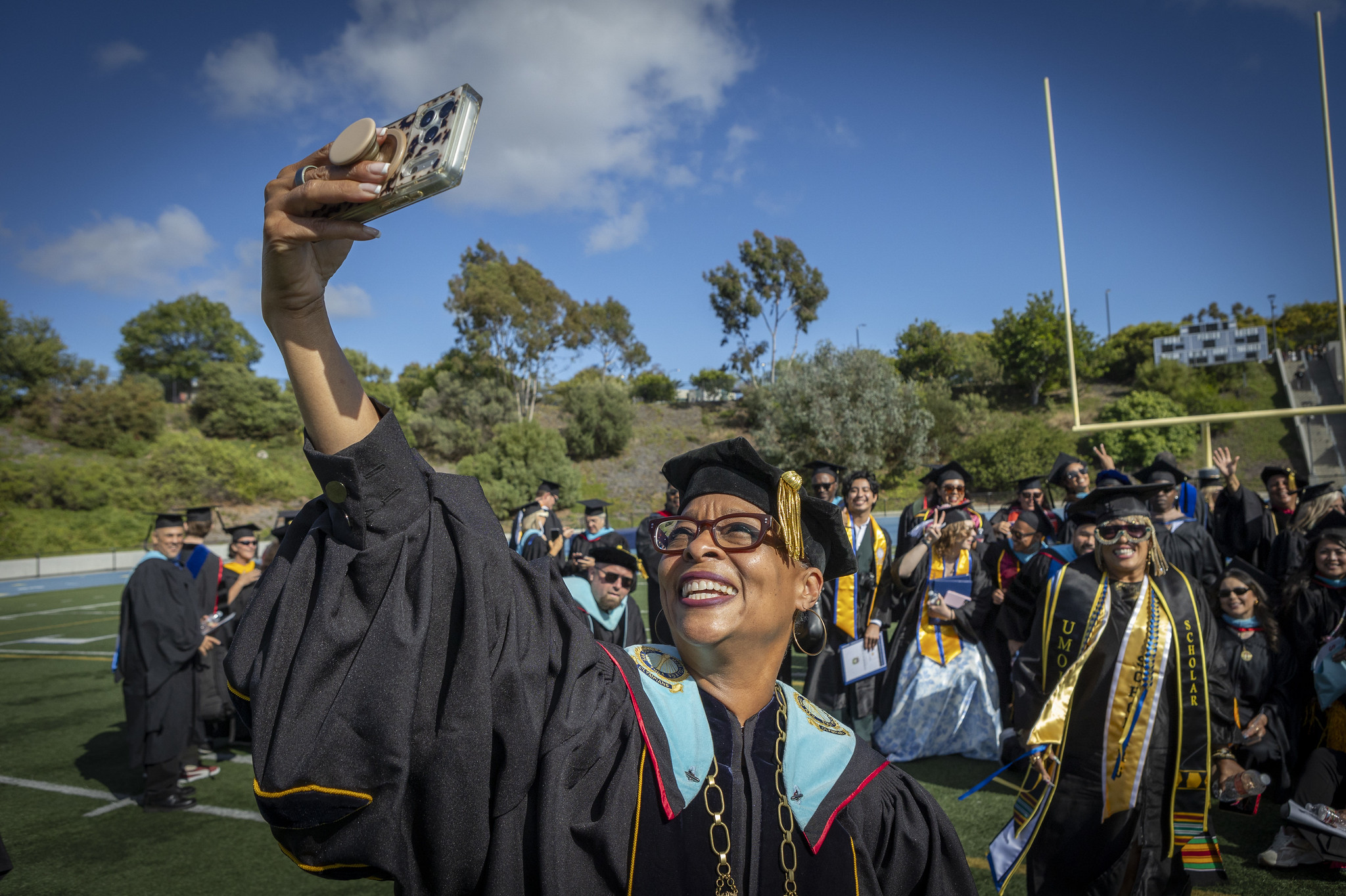 Mesa College President Ashanti Hands takes a selfie with graduates and faculty.