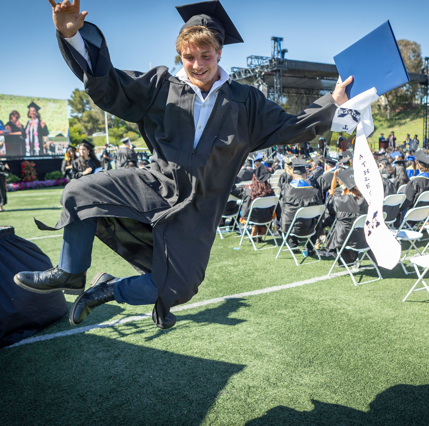 Graduate jumps in the aire and clicks his heels together.&nbsp;