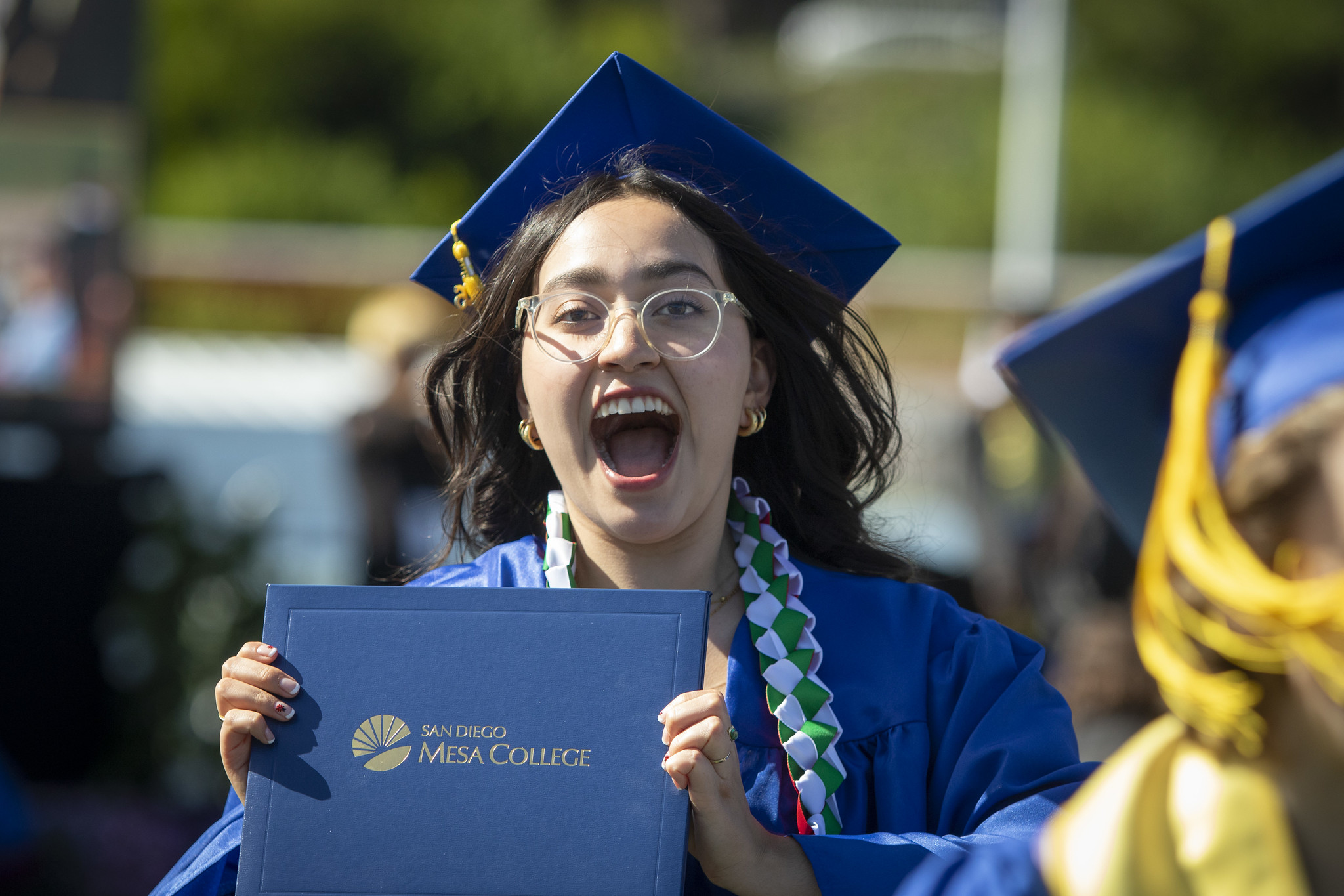 A grad screams and holds up her degree.&nbsp;