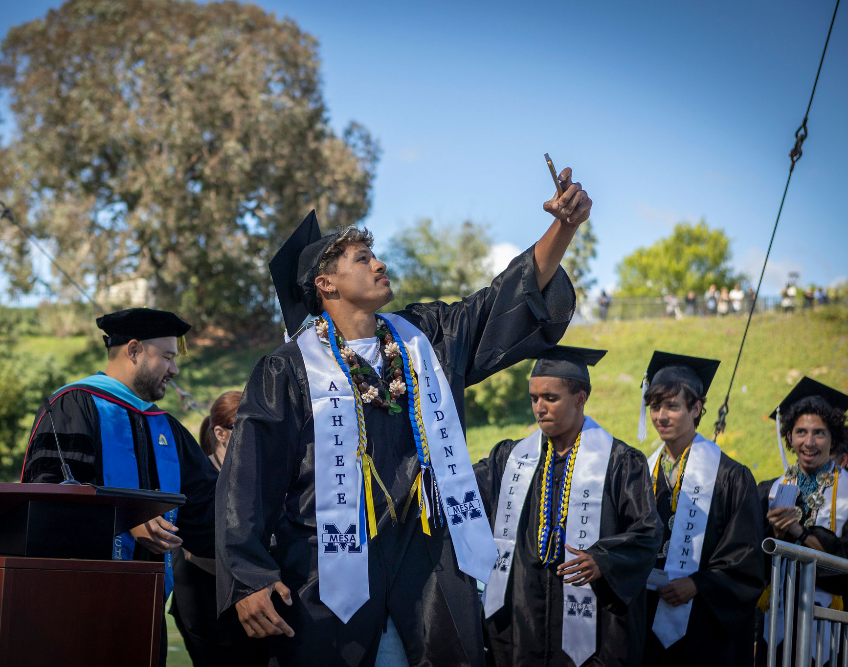 A grad takes a selfie on the graduation stage.