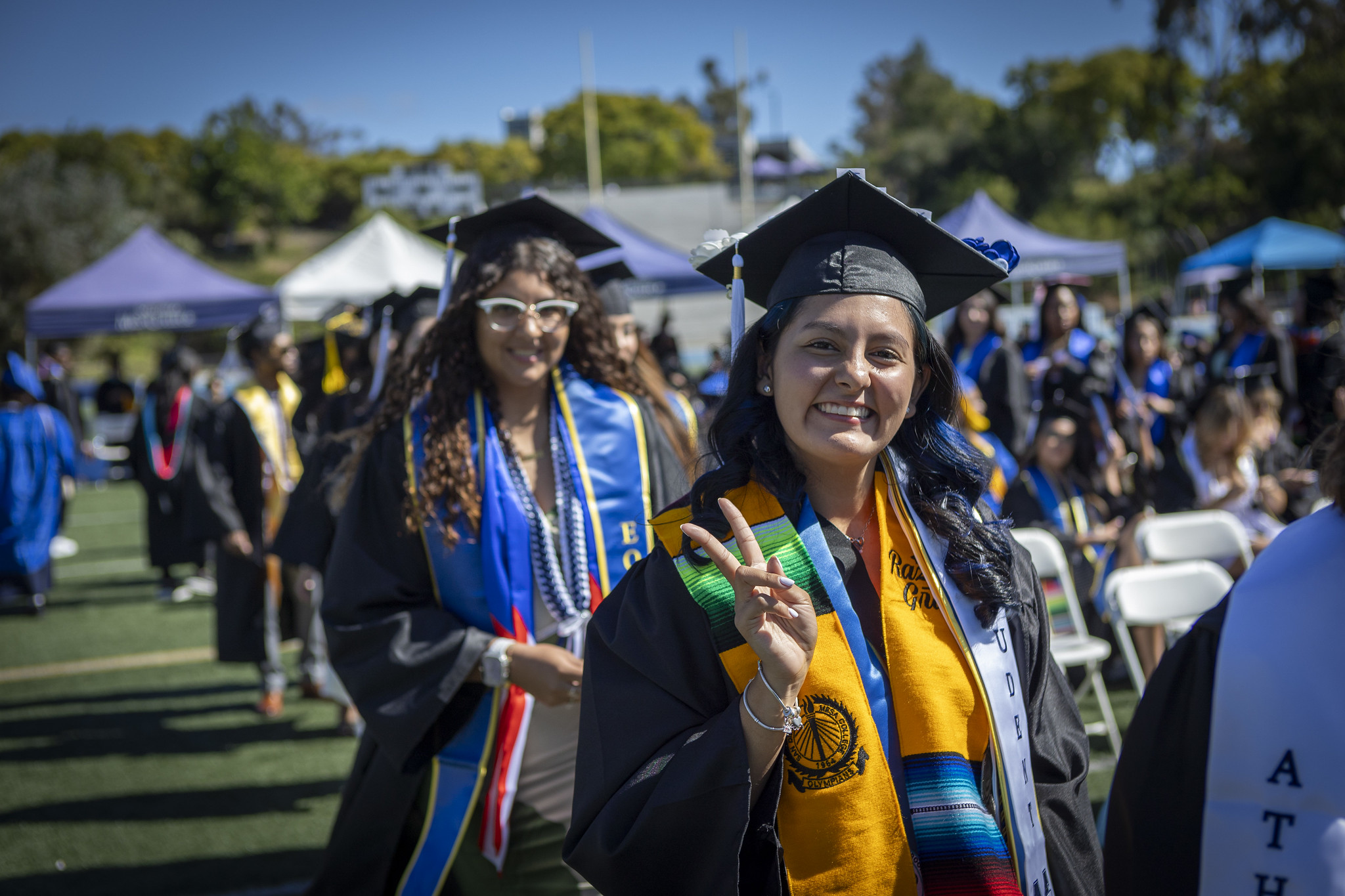A grad holds up a peace sign on the way to their seat.&nbsp;