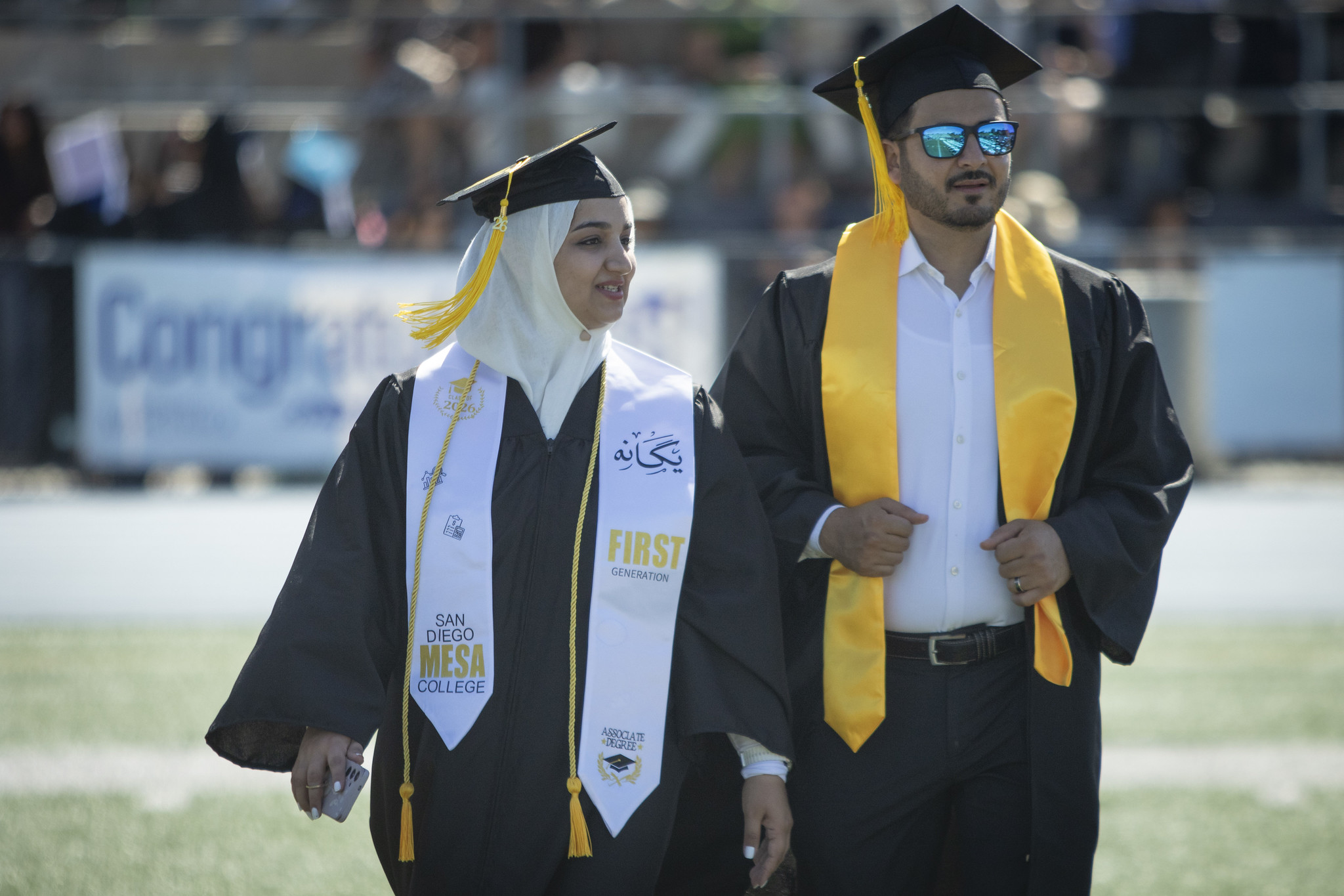 Two grads head to their seat.&nbsp;
