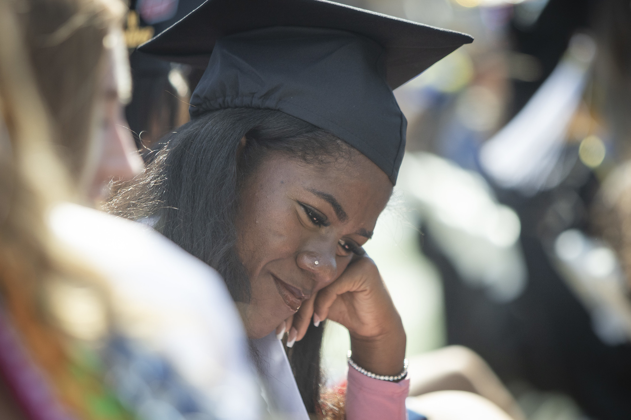 A close up of a grad with her head bowed down and smiling while seated in the audience.