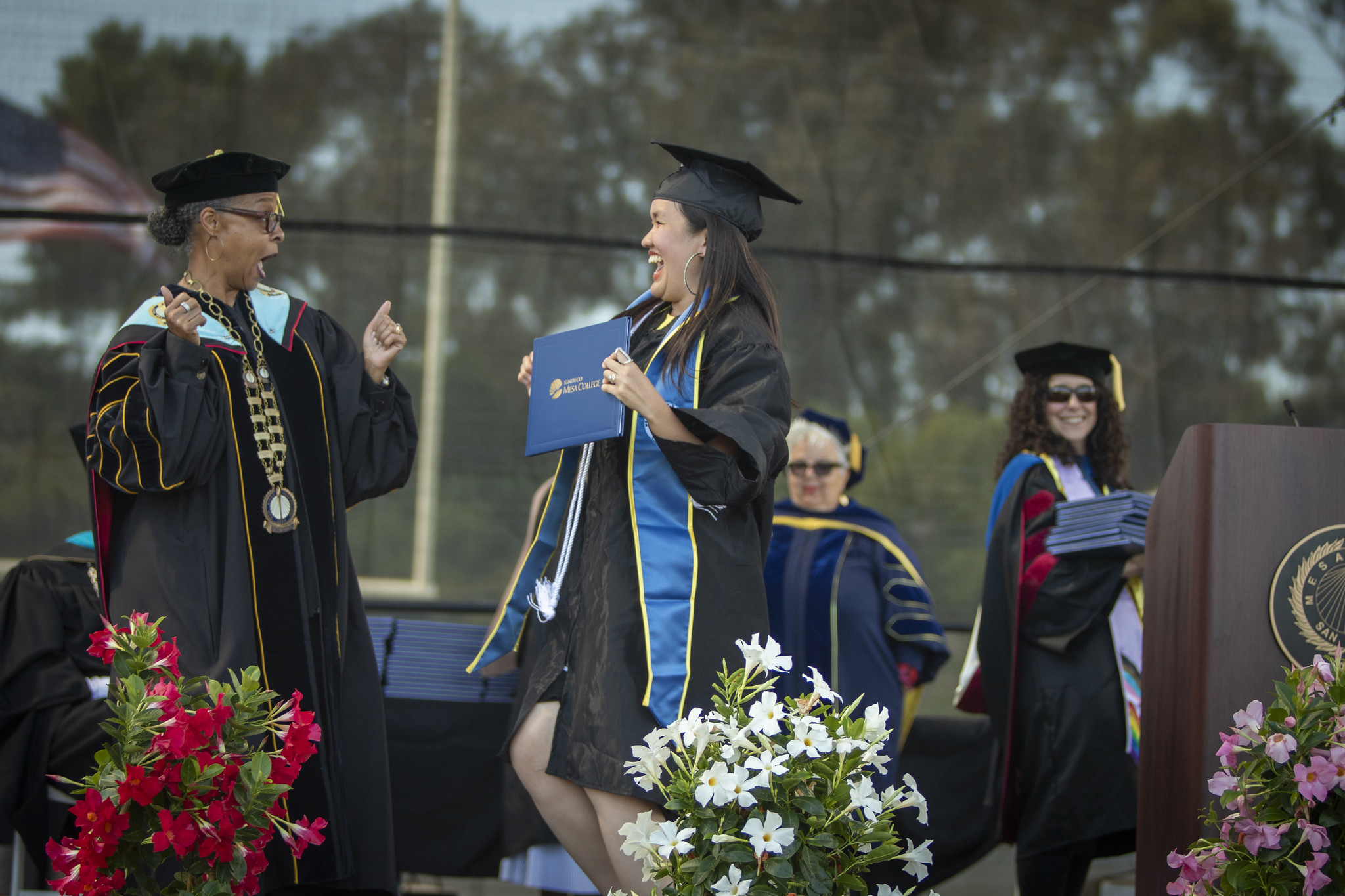 Mesa College President Ashanti Hands and a student share a moment and cheer as she receives her diploma.&nbsp;