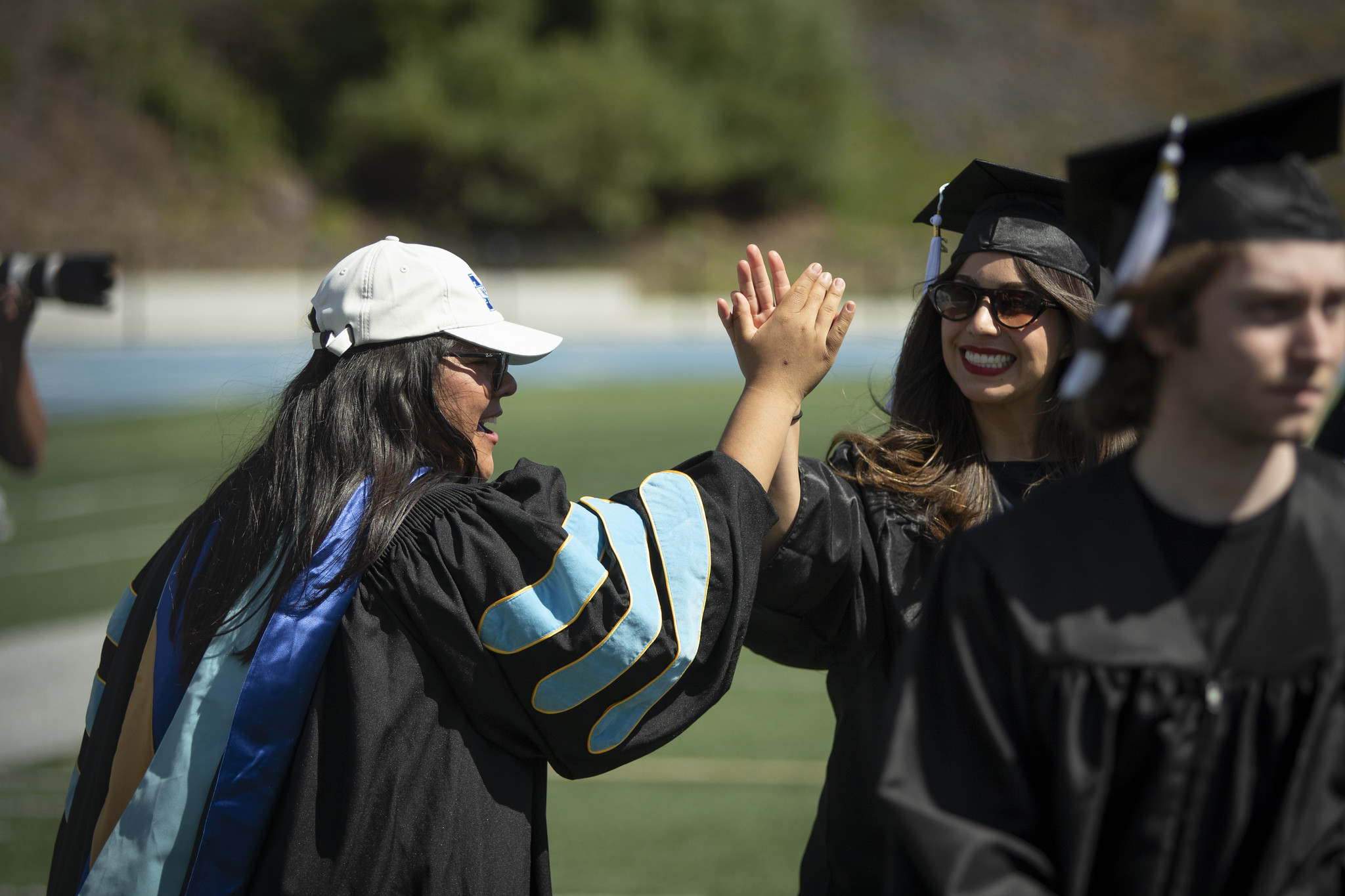 Two people high five as the grads are walking into the ceremony.&nbsp;