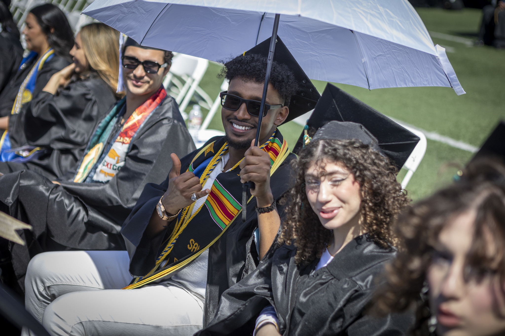 A grad in the audience holding a silver umbrella.&nbsp;