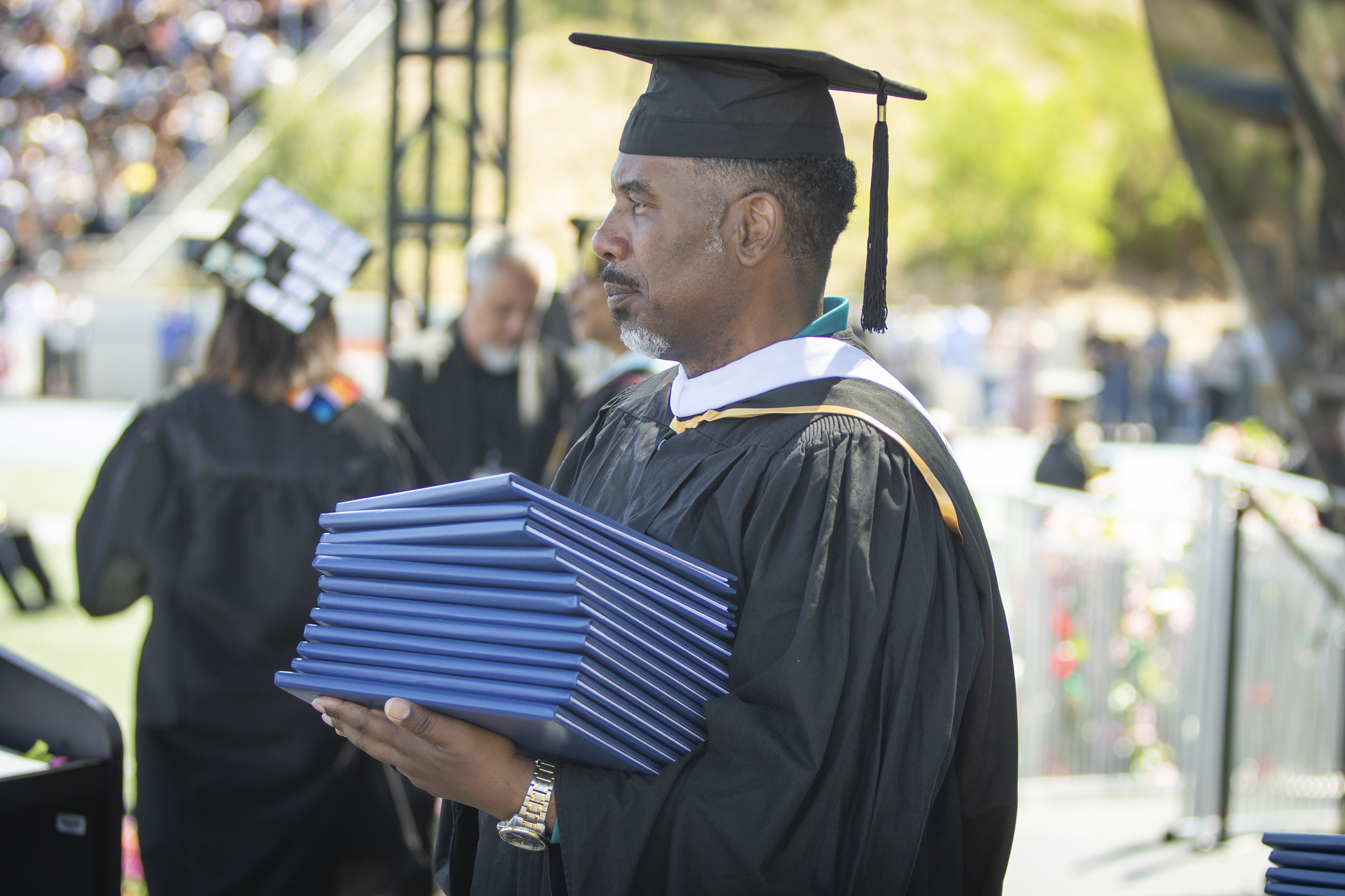 A faculty member holding a stack of degrees.&nbsp;