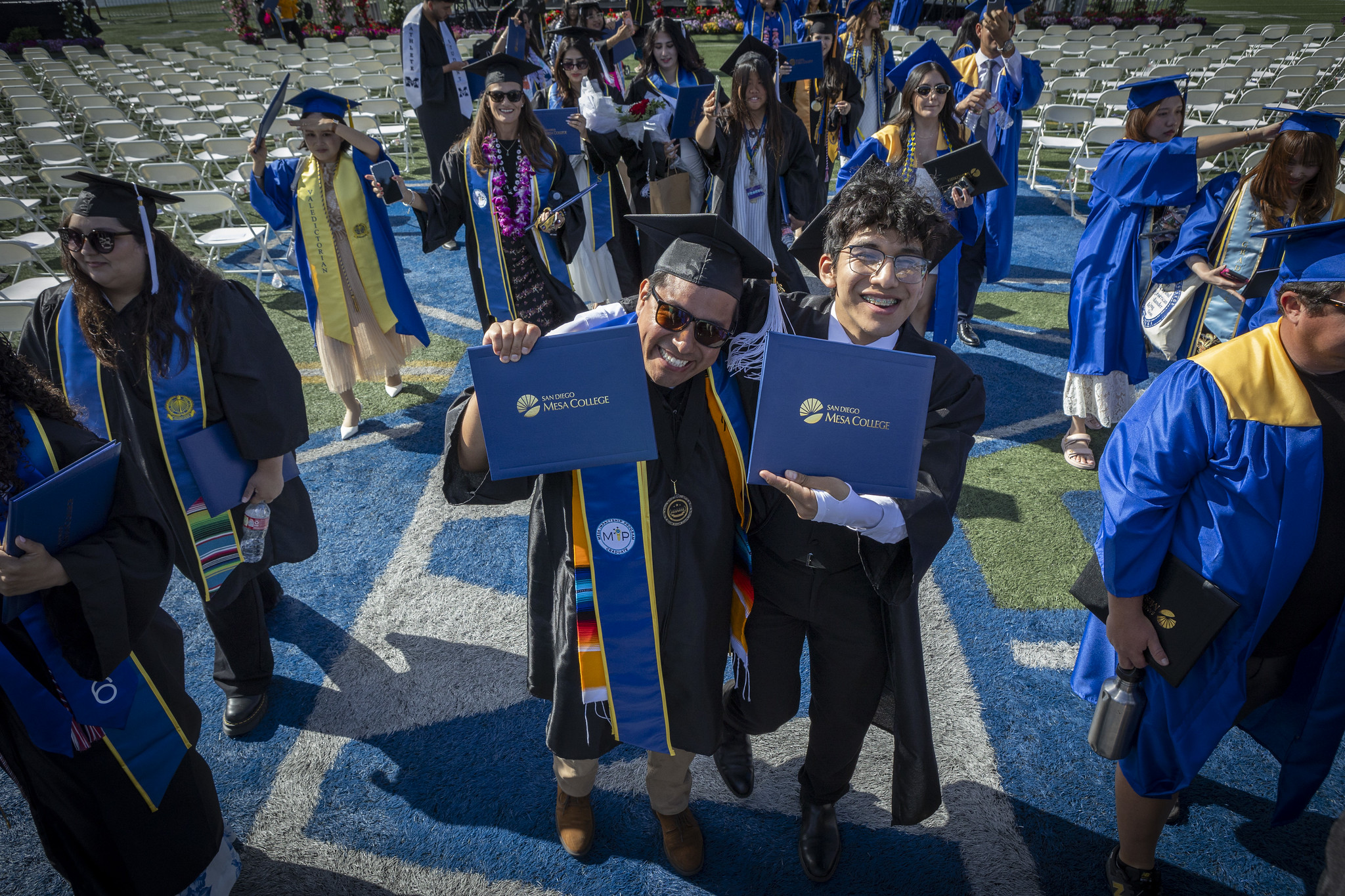 Two grads hold up their degrees.&nbsp;