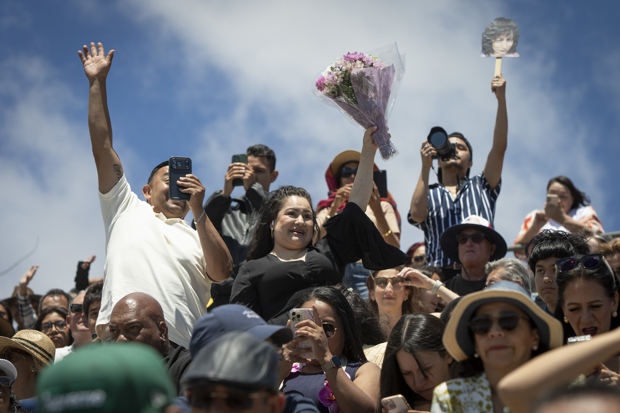 Family members in the bleachers standing up cheering and waving.&nbsp;