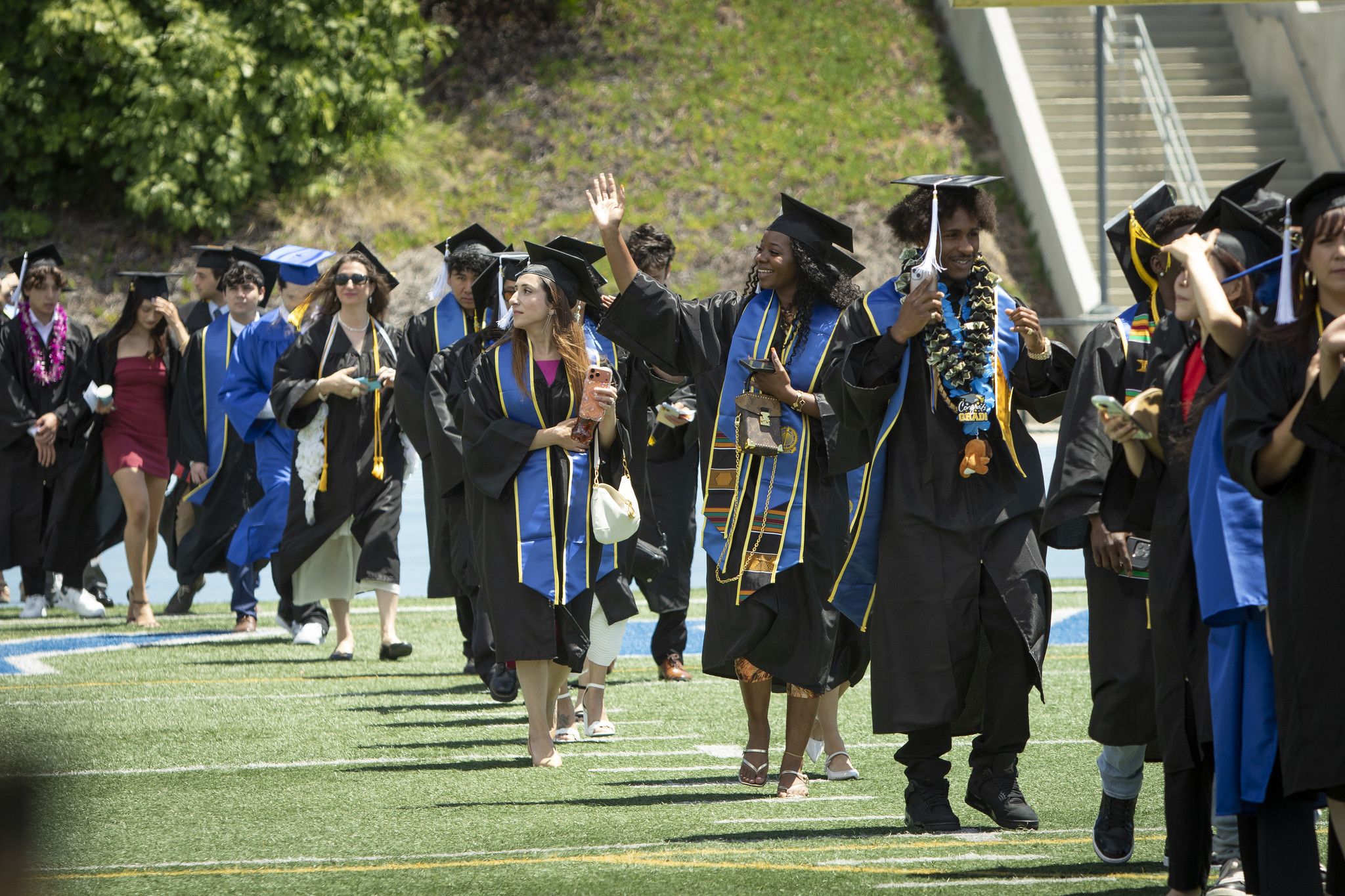 Graduates walking on the field to their seats at the start of the ceremony.