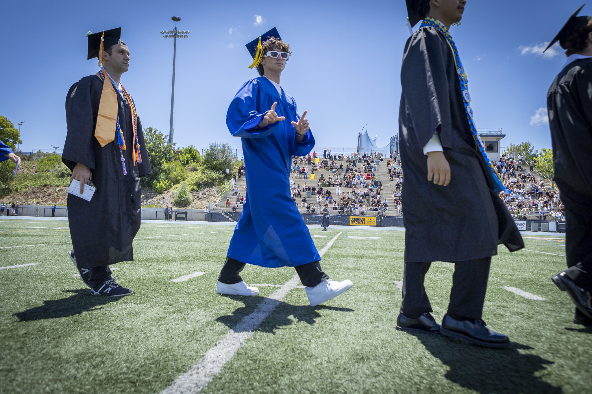 Graduates walking on the field to their seats at the start of the ceremony.