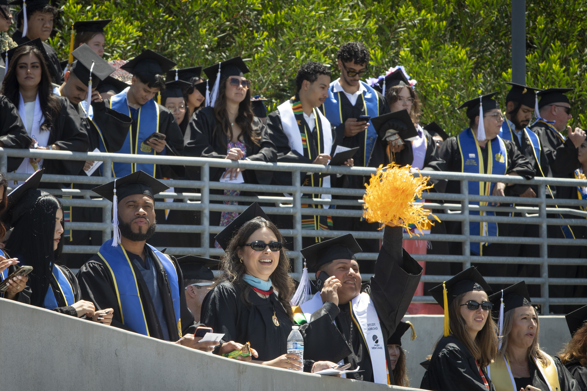 Graduates walk down the stadium ramp toward the grass field.&nbsp;&nbsp;