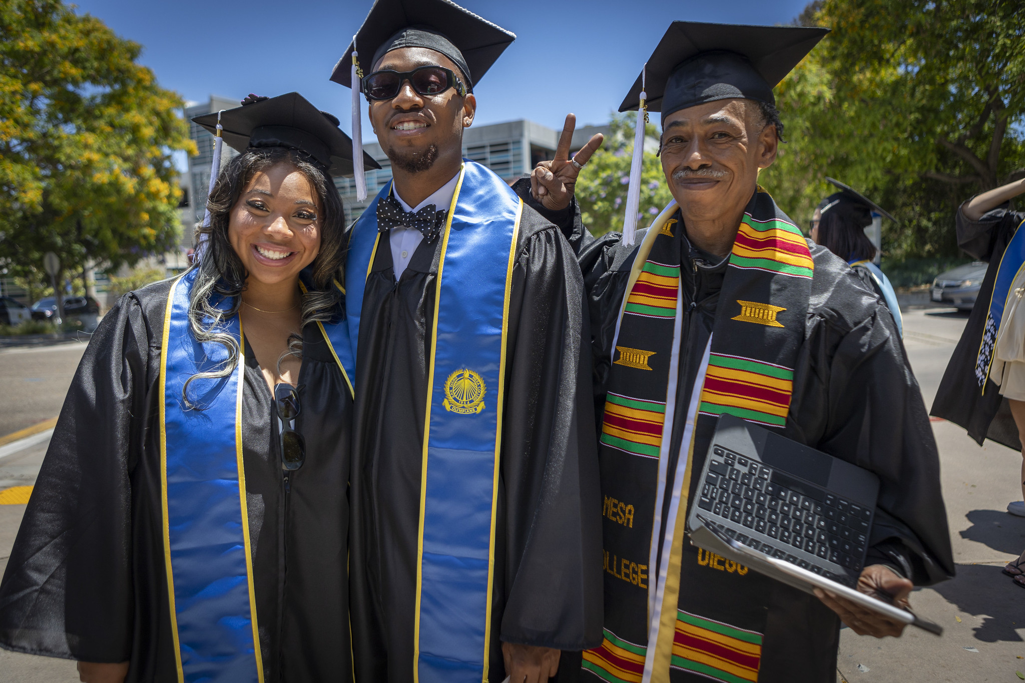 Two graduates with a faculty member.&nbsp;
