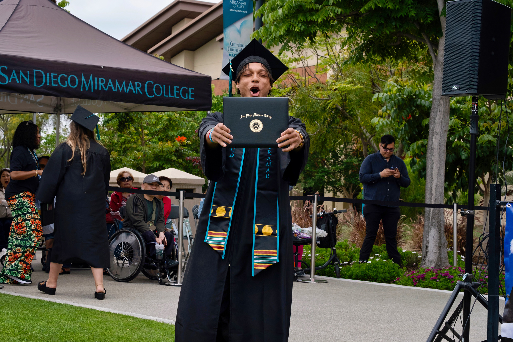 A student holds up their degree.