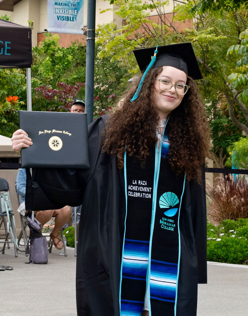 A student holds up their degree.