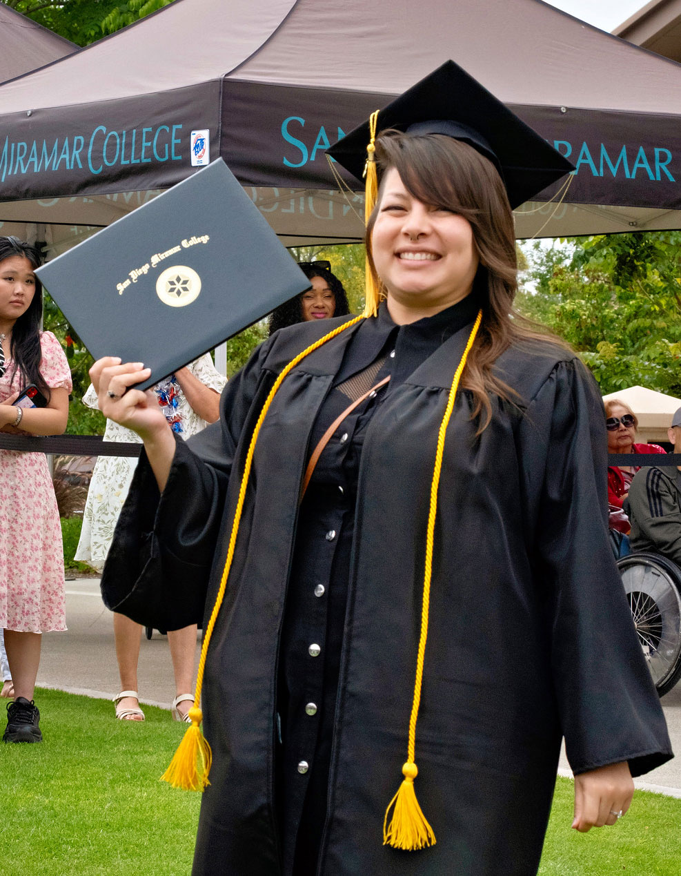 A student holds up their degree.