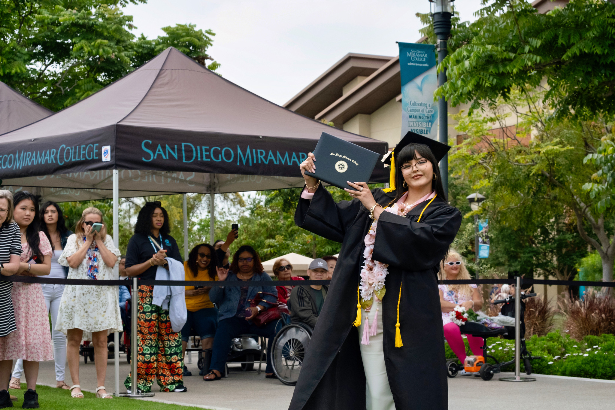 A student holds up their degree.