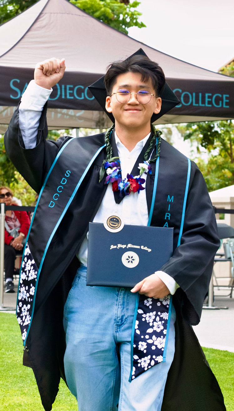 A student holds up their degree.