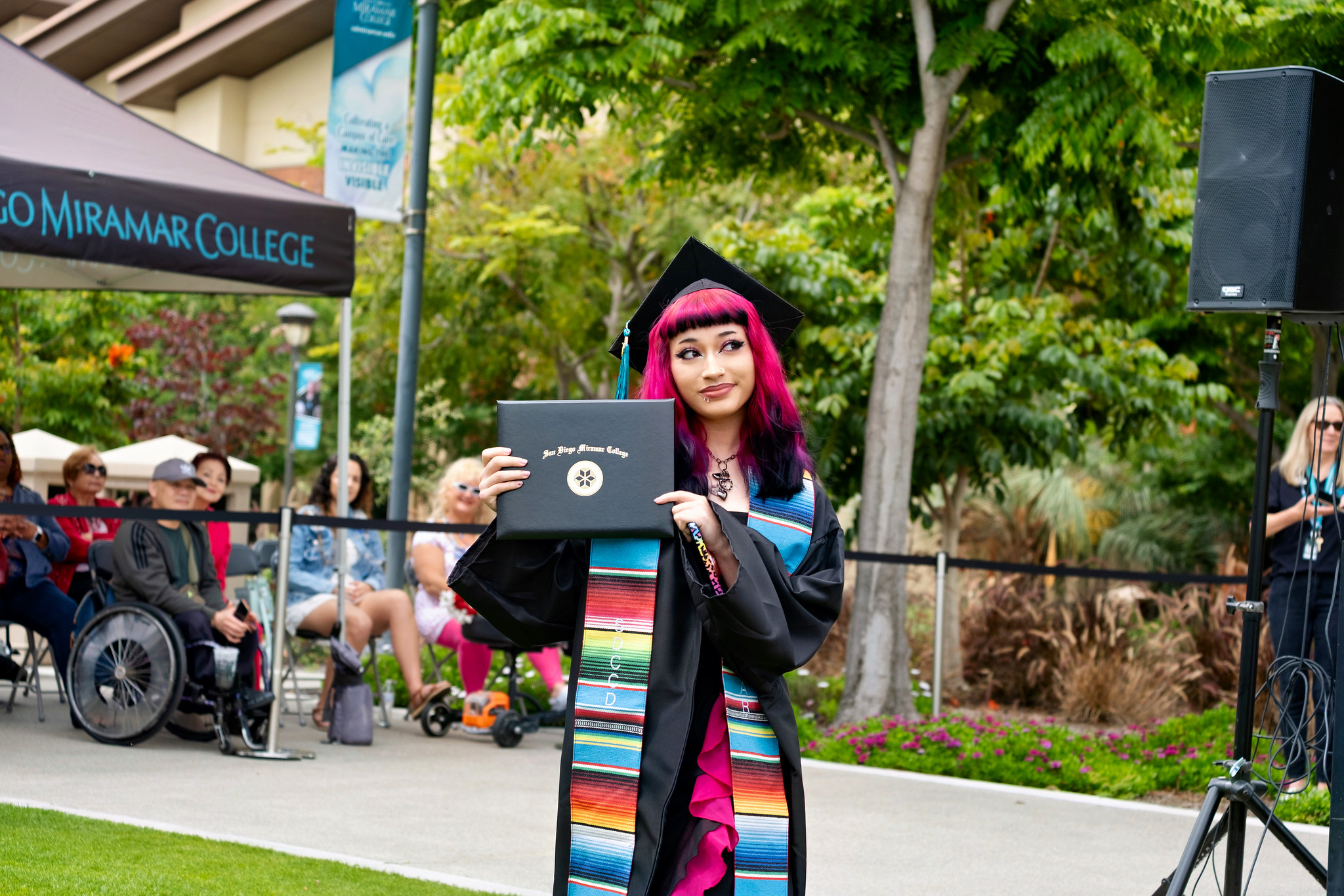 A student holds up her degree.