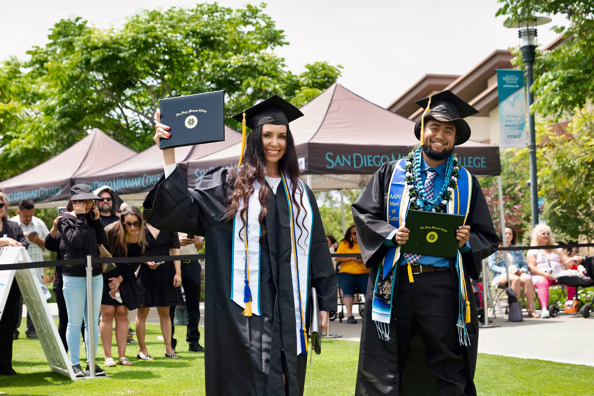 Two students hold up their degrees.