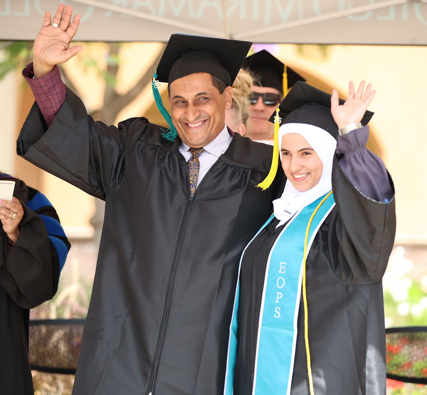 A father and daughter who graduated together waves from the stage.&nbsp;