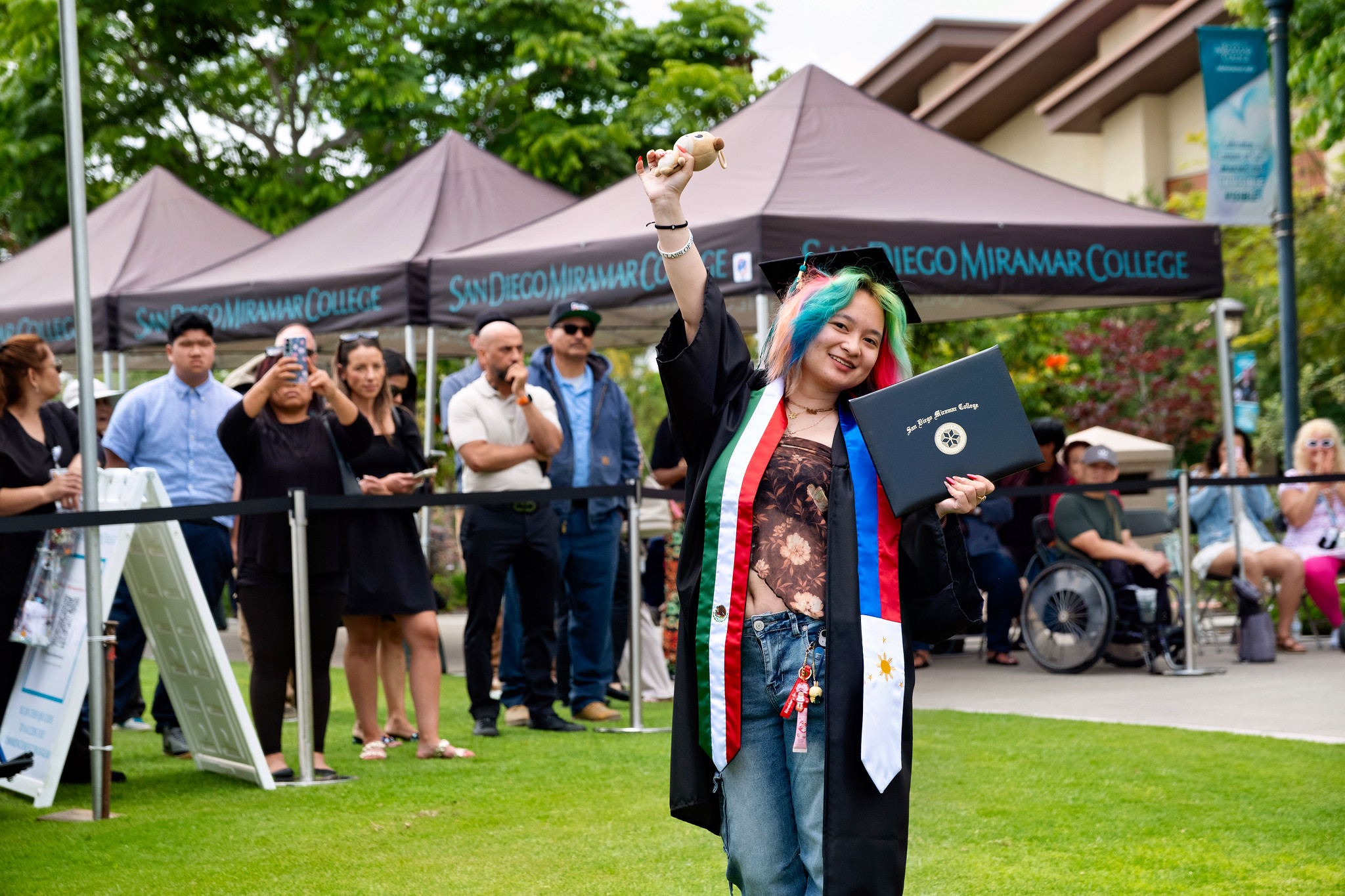 A student holds up their degree