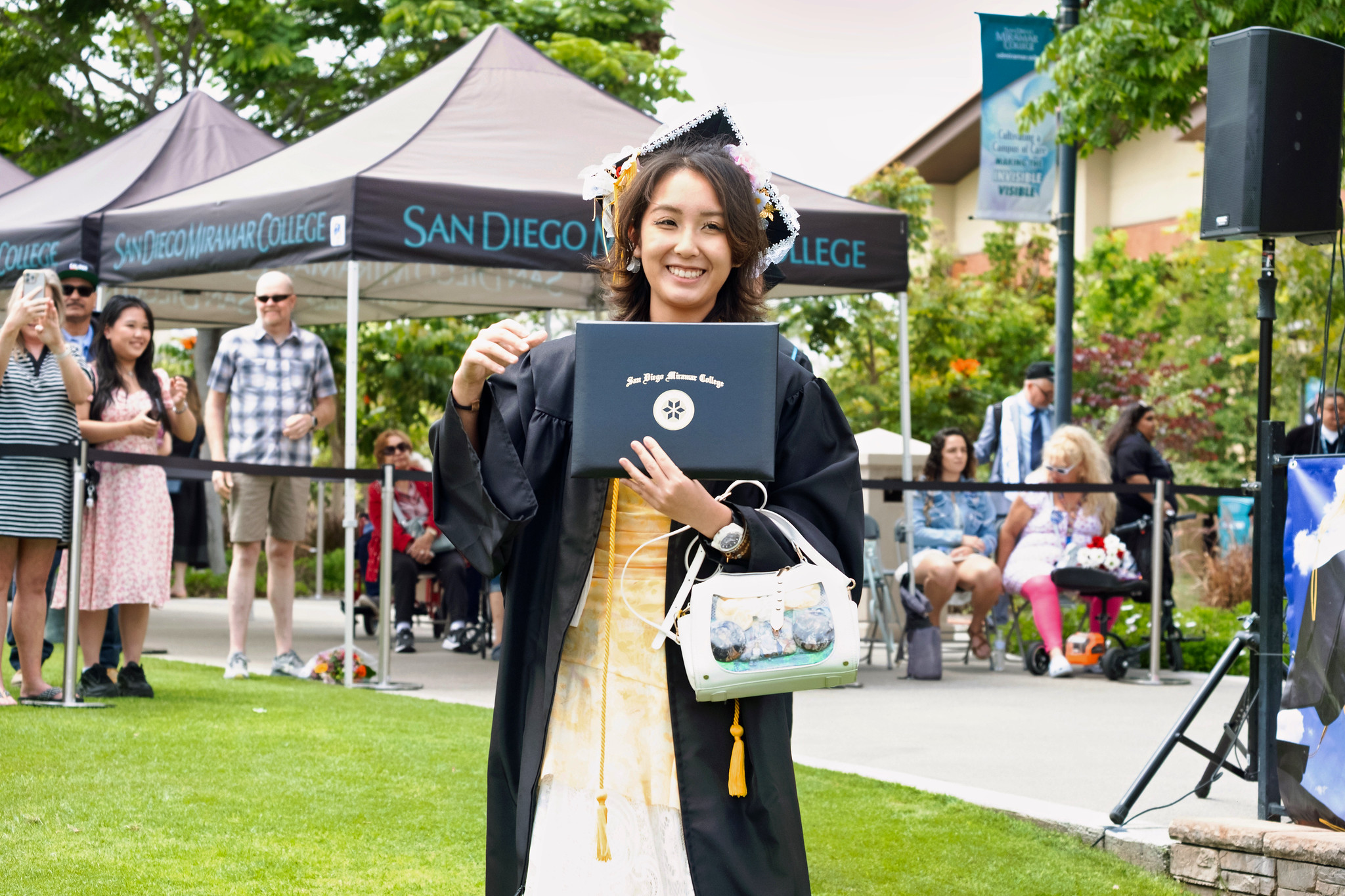 A student holds up their degree