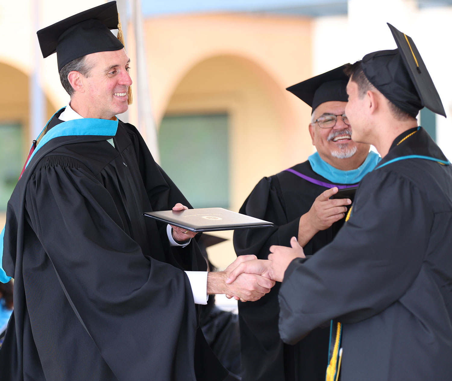 Chancellor Smith hands a graduate their degree.