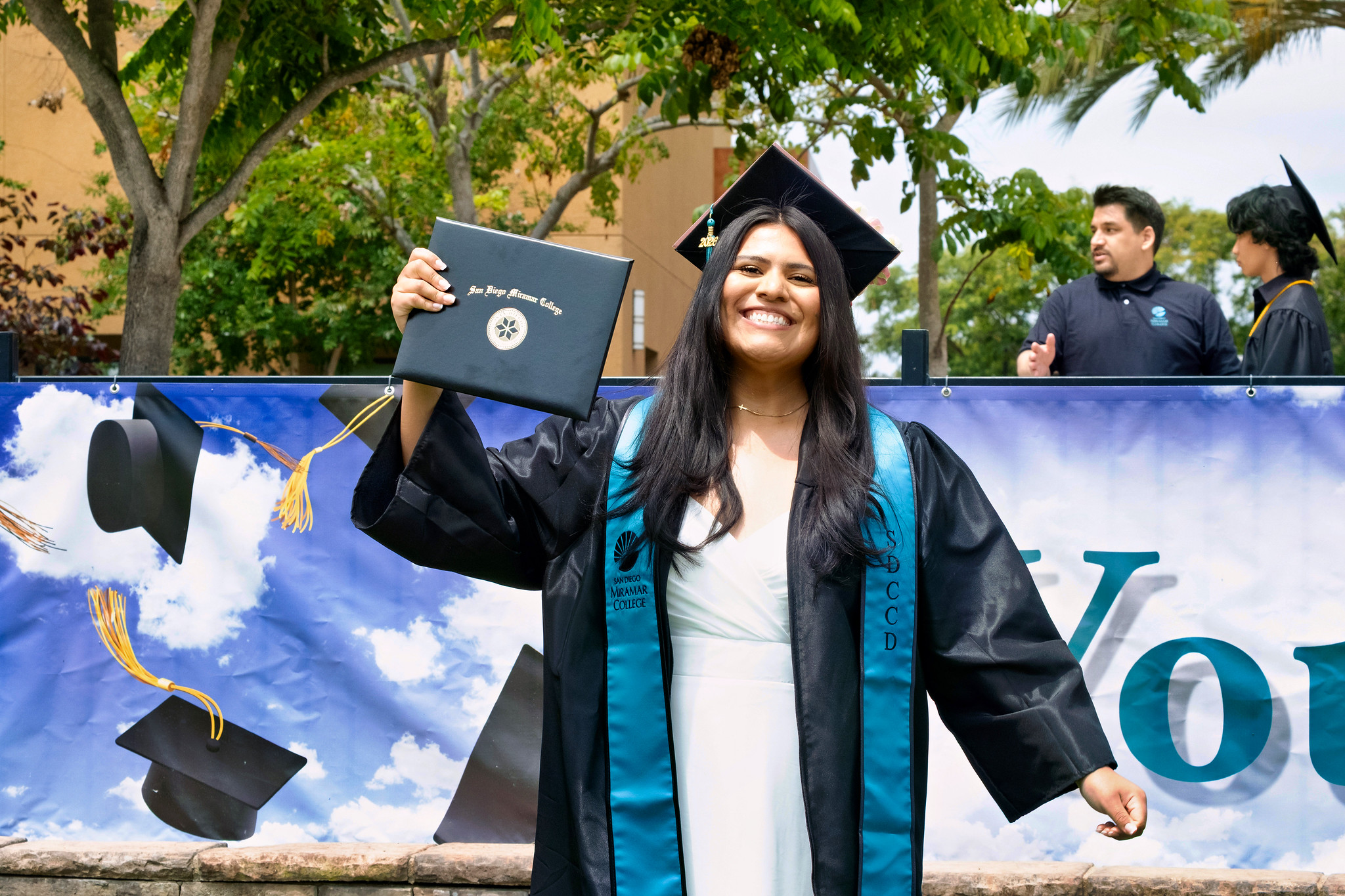A student holds up their degree.