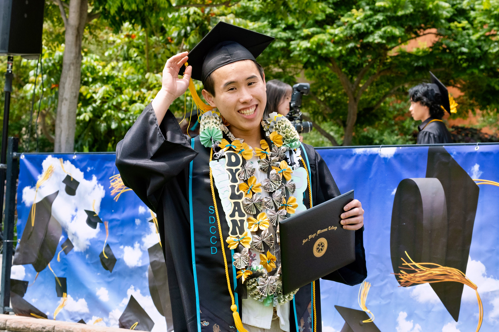 A student holds up their degree.