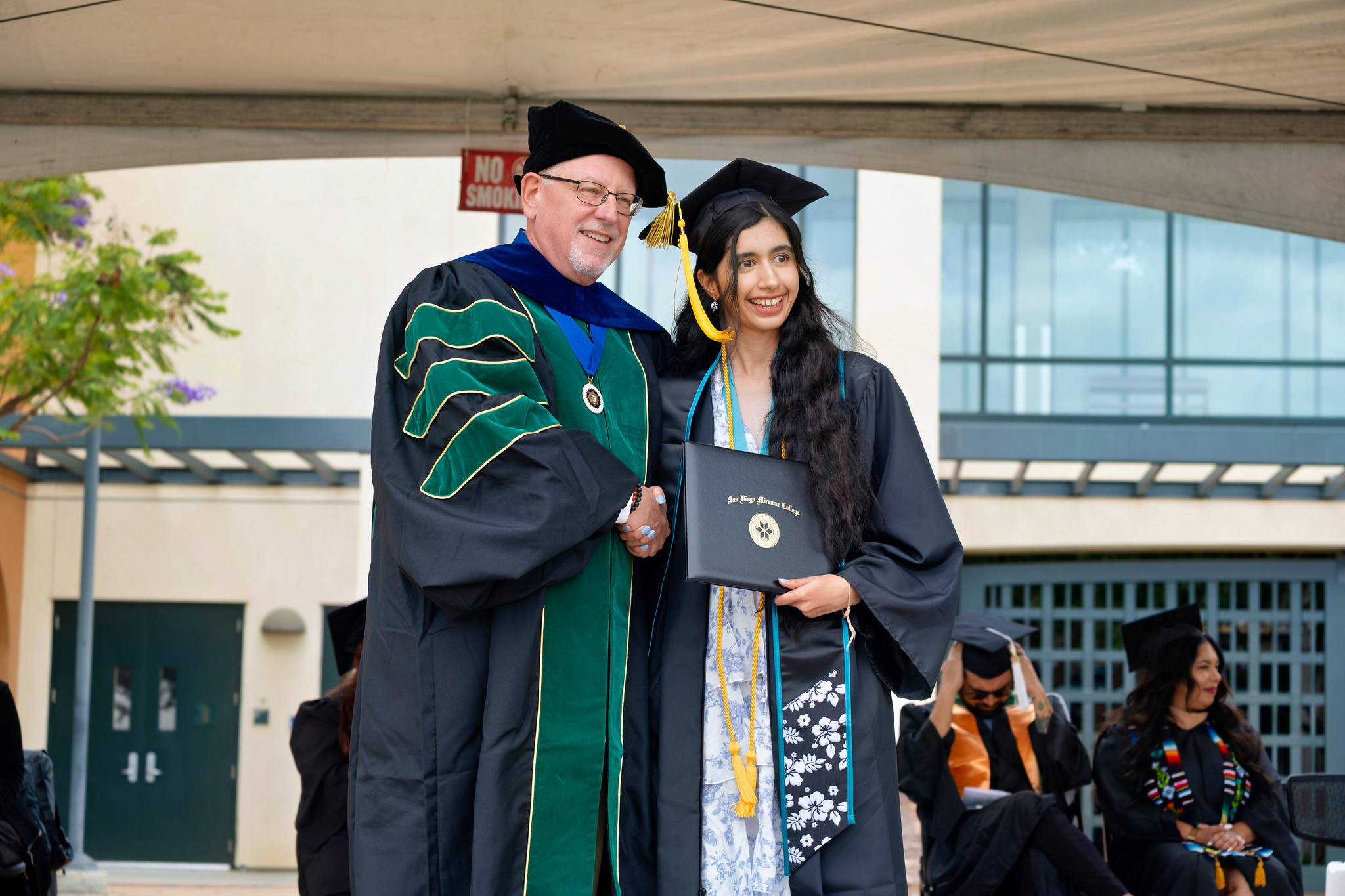 Miramar College President Wes Lundburg hands a graduate her degree.&nbsp;
