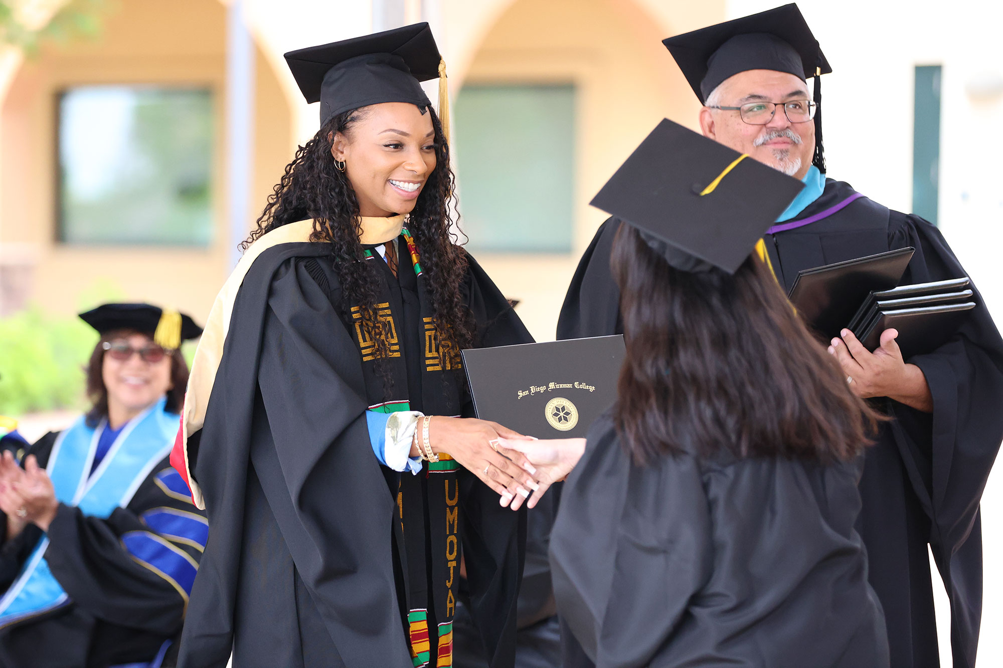 Trustee Mariah Jameson hands a graduate their degree.