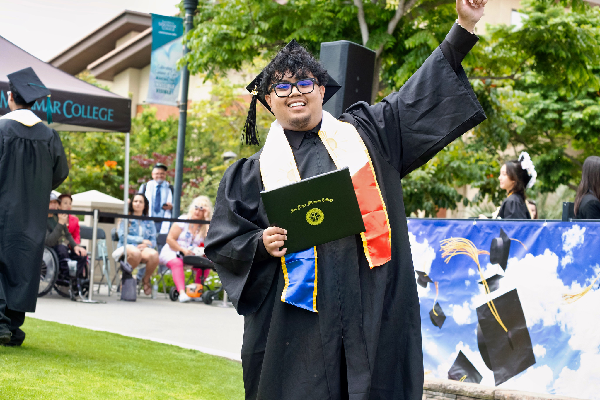 A student holds up their degree.