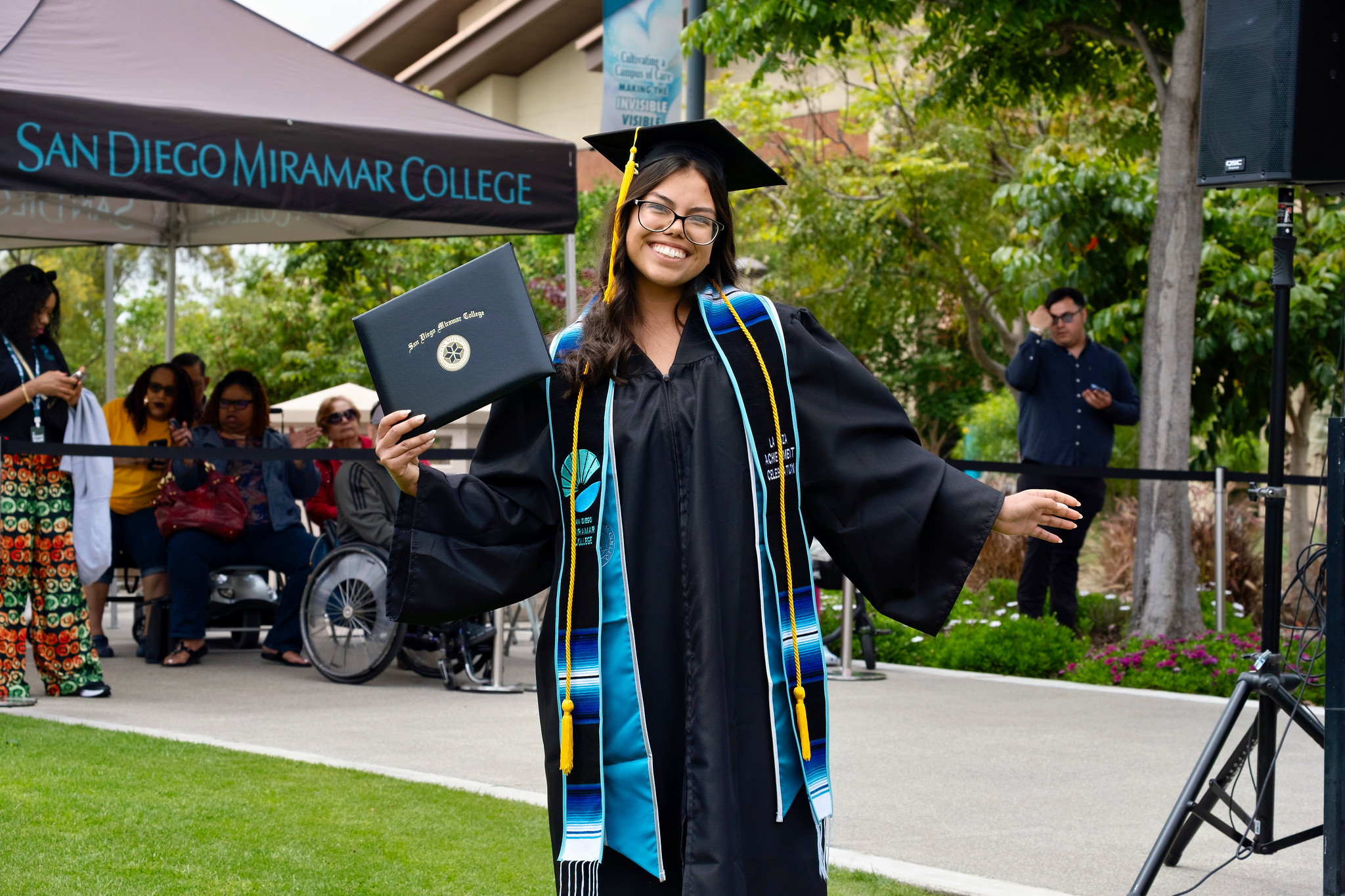 A student holds up their degree.