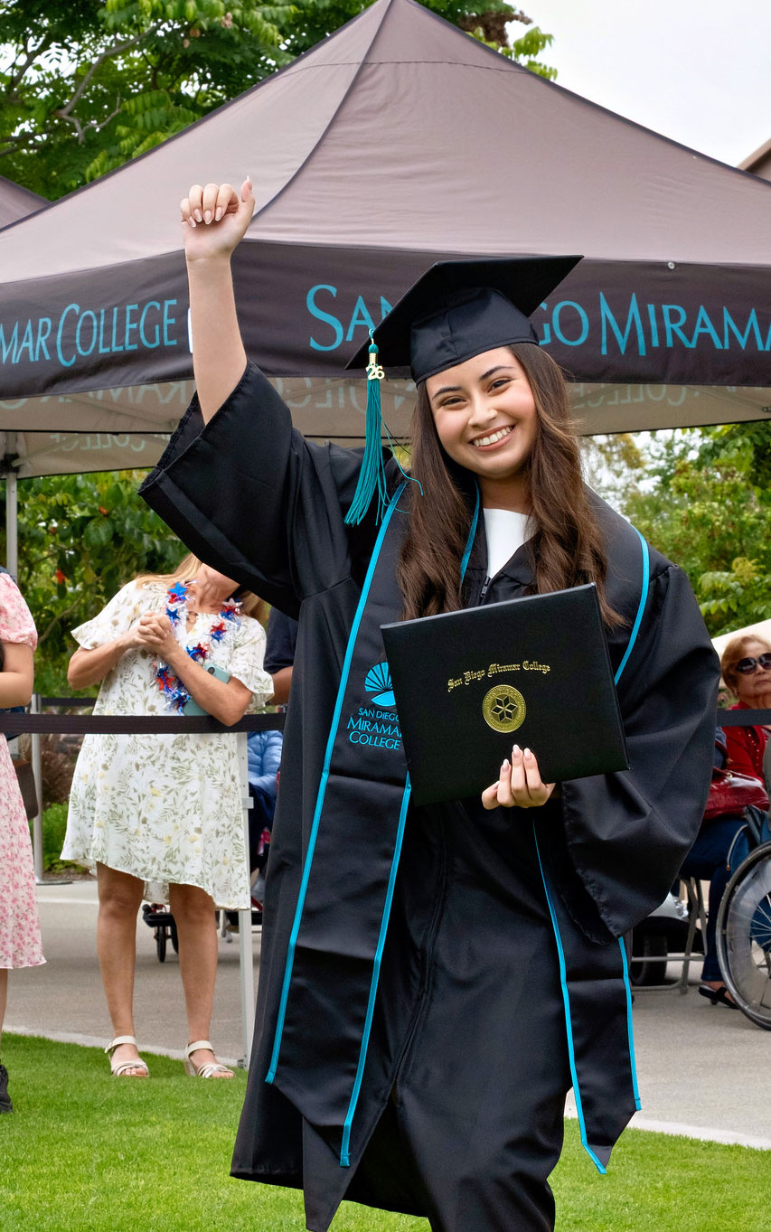A student holds up their degree.