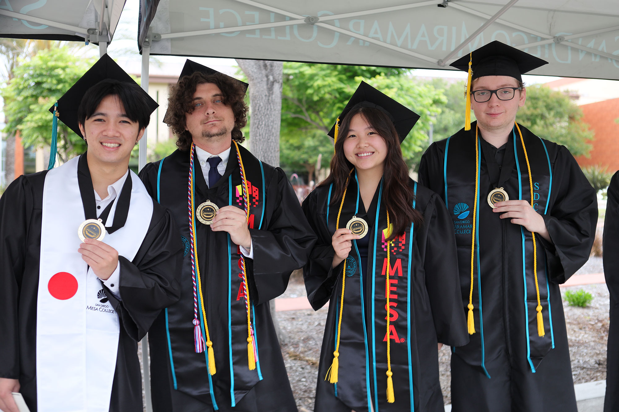 Four graduates who were in the San Diego Promise program hold up their Promise medallions.&nbsp;