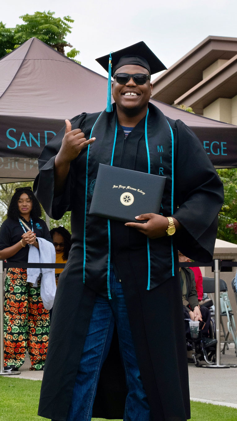 A student holds up their degree.