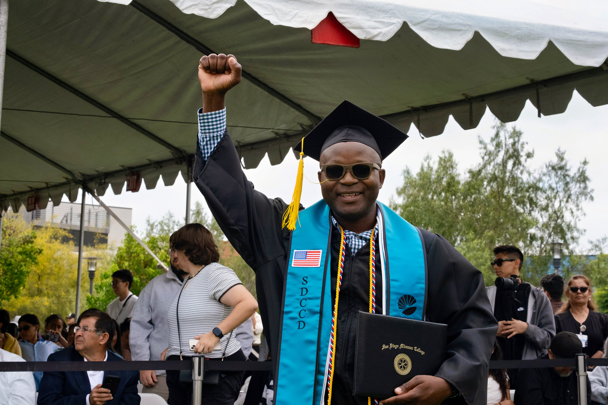 A student holds up their degree.
