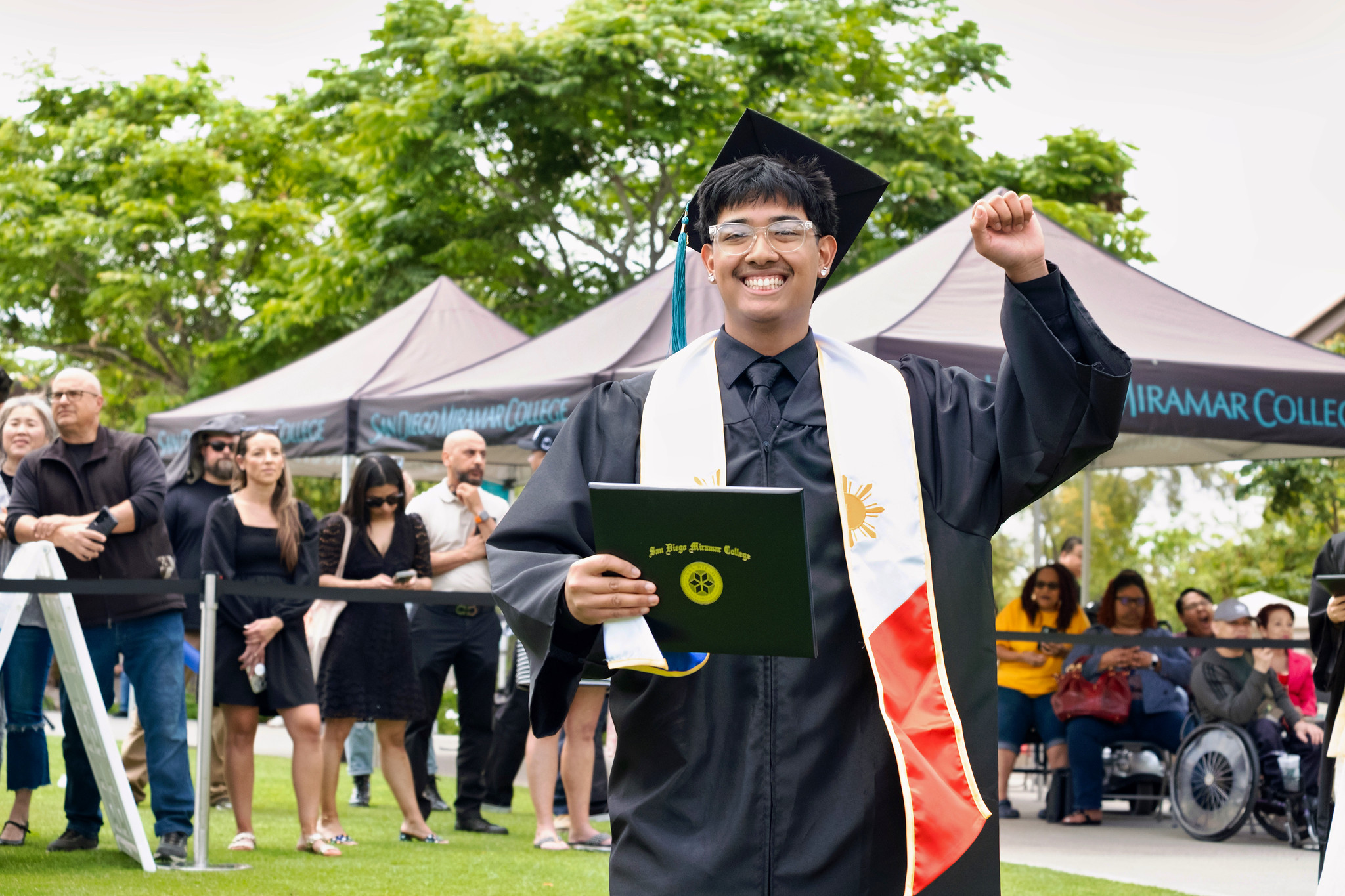 A student holds up their degree.