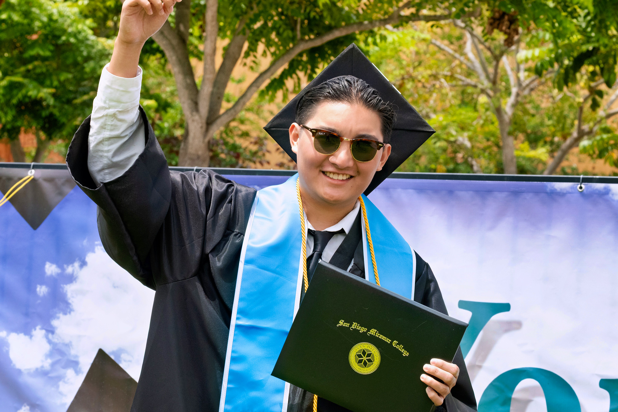 A student holds up their degree.