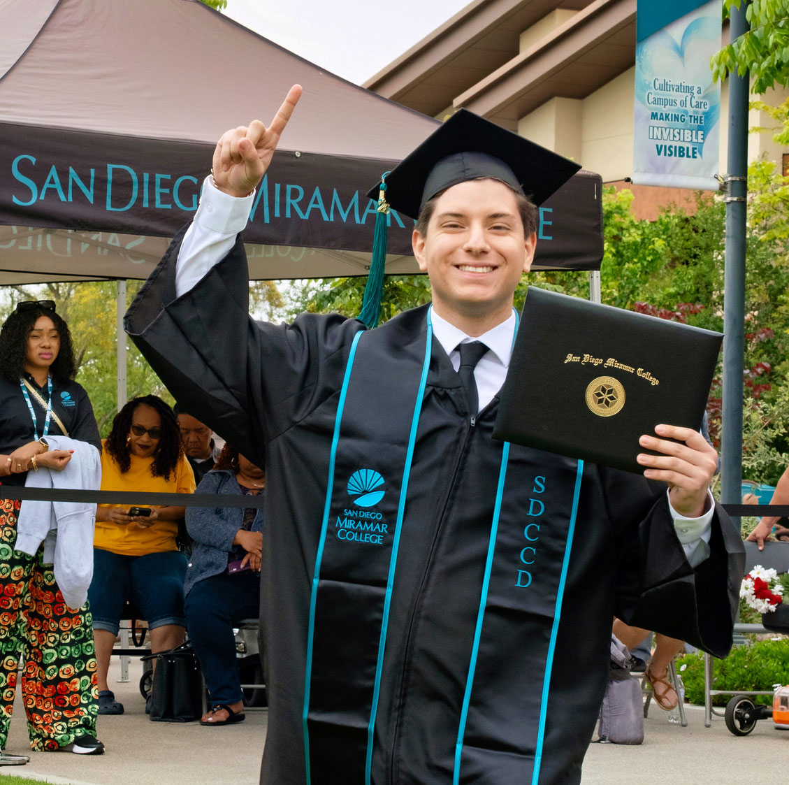 A student holds up their degree.