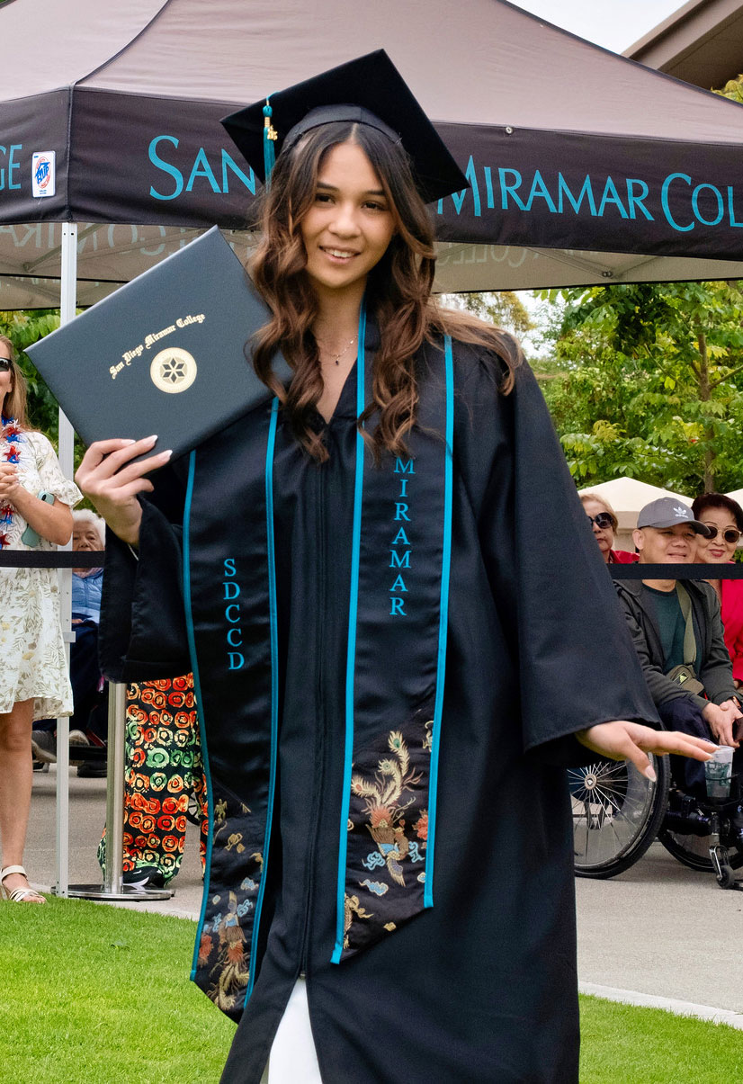 A student holds up their degree.