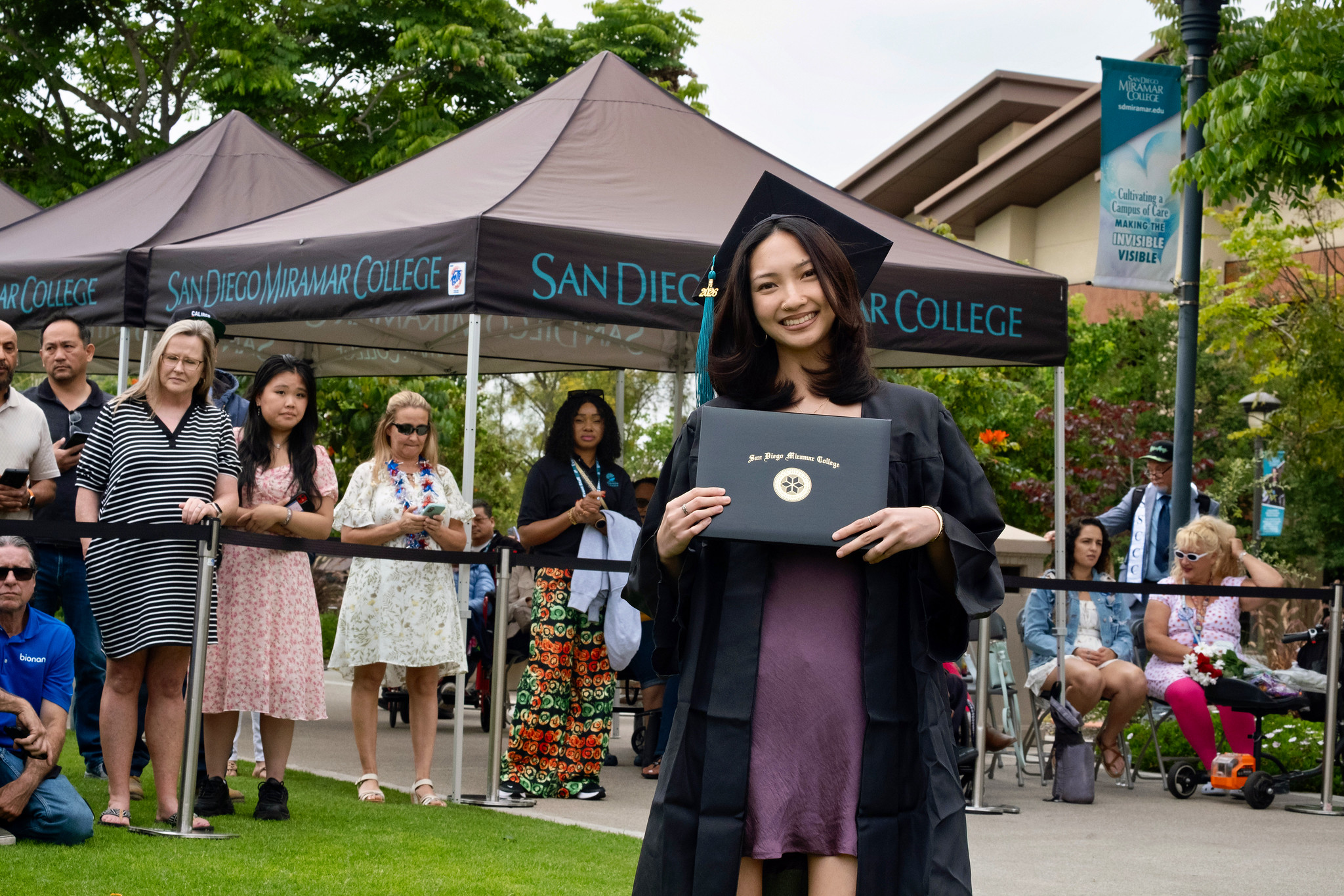 A student holds up their degree.