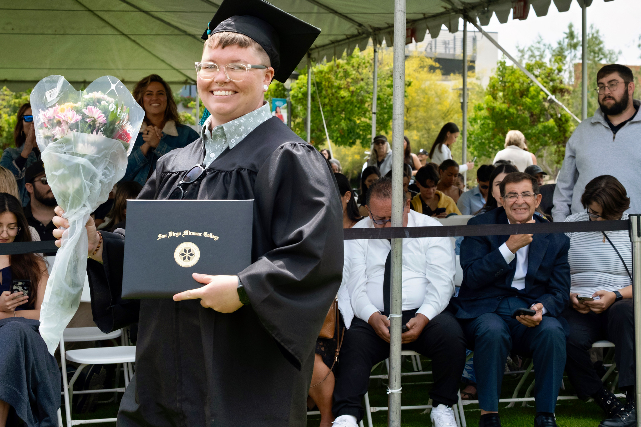 A student holds up their degree.