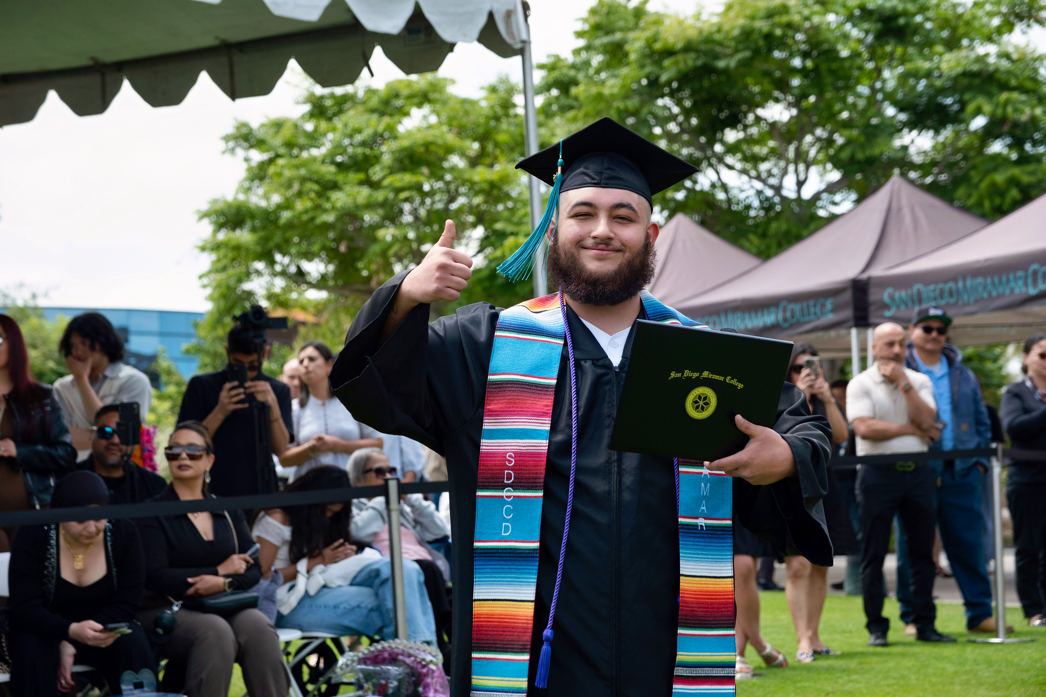 A student holds up their degree.