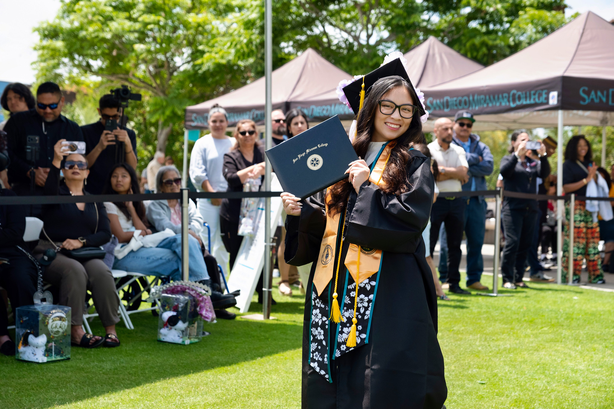 A student holds up their degree.