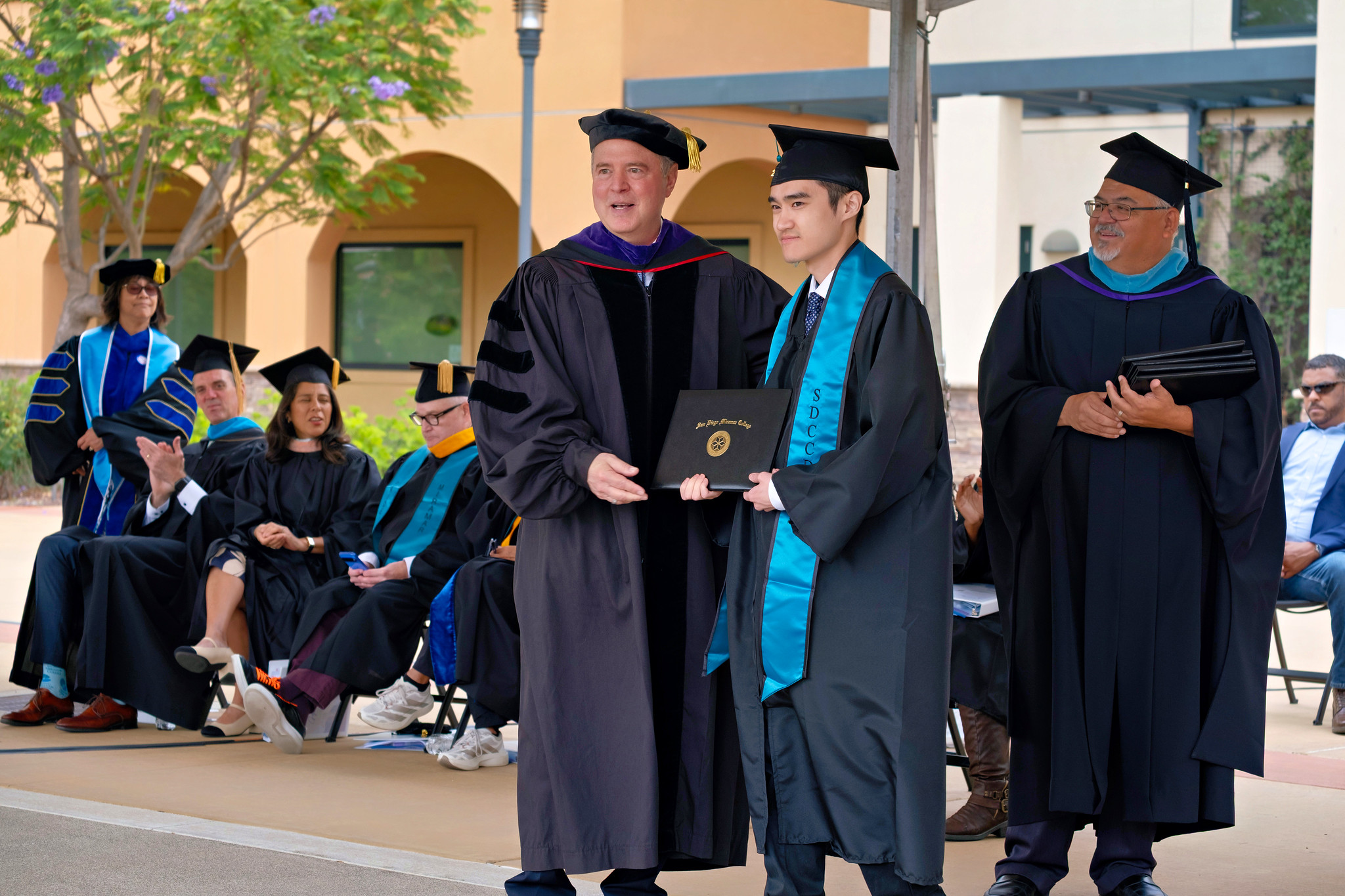 U.S. Senator Adam Schiff hands a degree to a graduate.