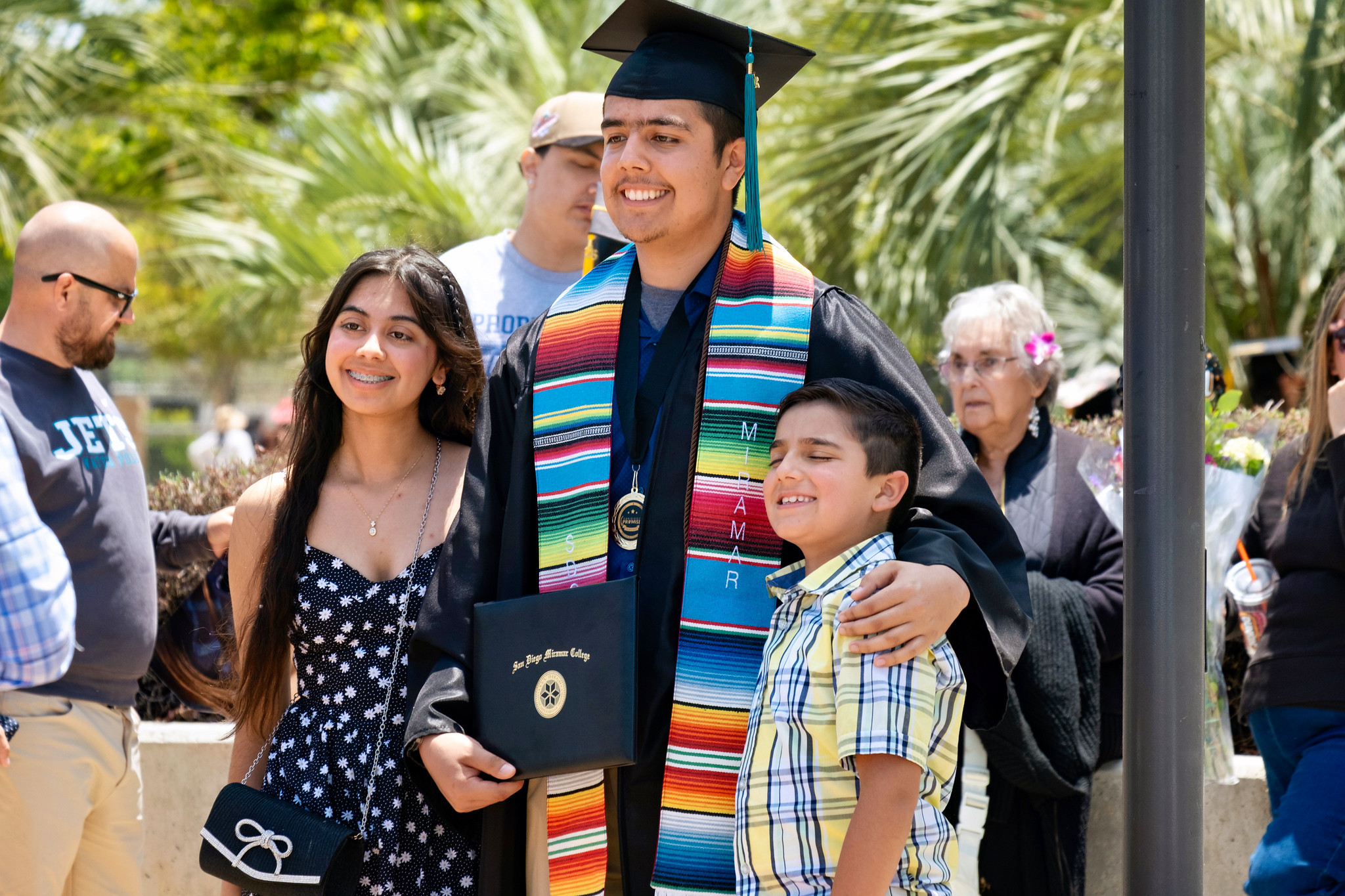 A graduate poses for a photo with two children.